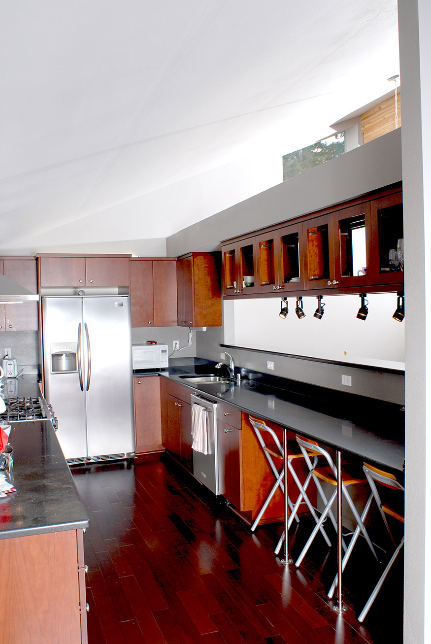 View of kitchen with vaulted ceiling open to open plan dining & living room